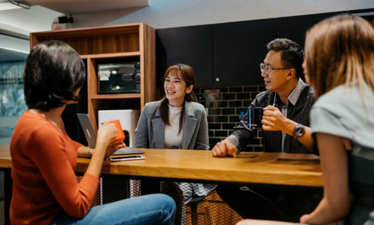Employees sitting at office pantry resting and eating snacks